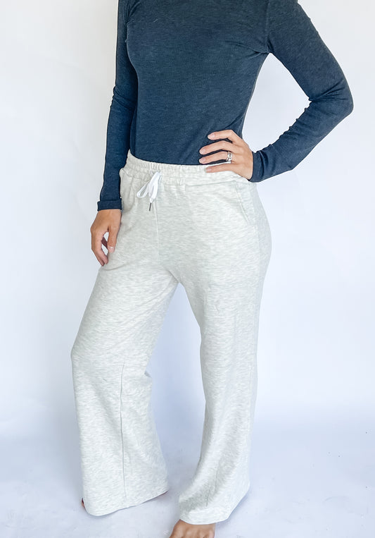 woman wearing a charoal long-sleeve top and light grey sweatpants on a white background