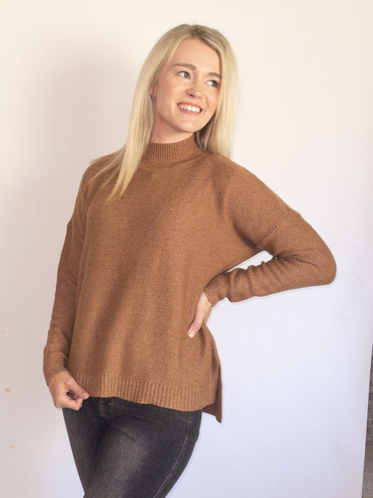 Woman wearing a mock neck brown sweater against a plain background