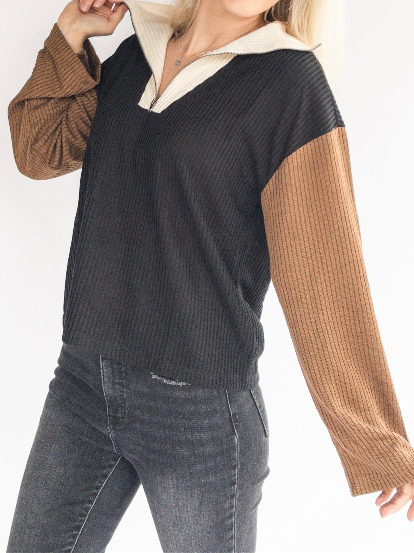 Woman wearing a black and brown sweater with a white collar on a white background