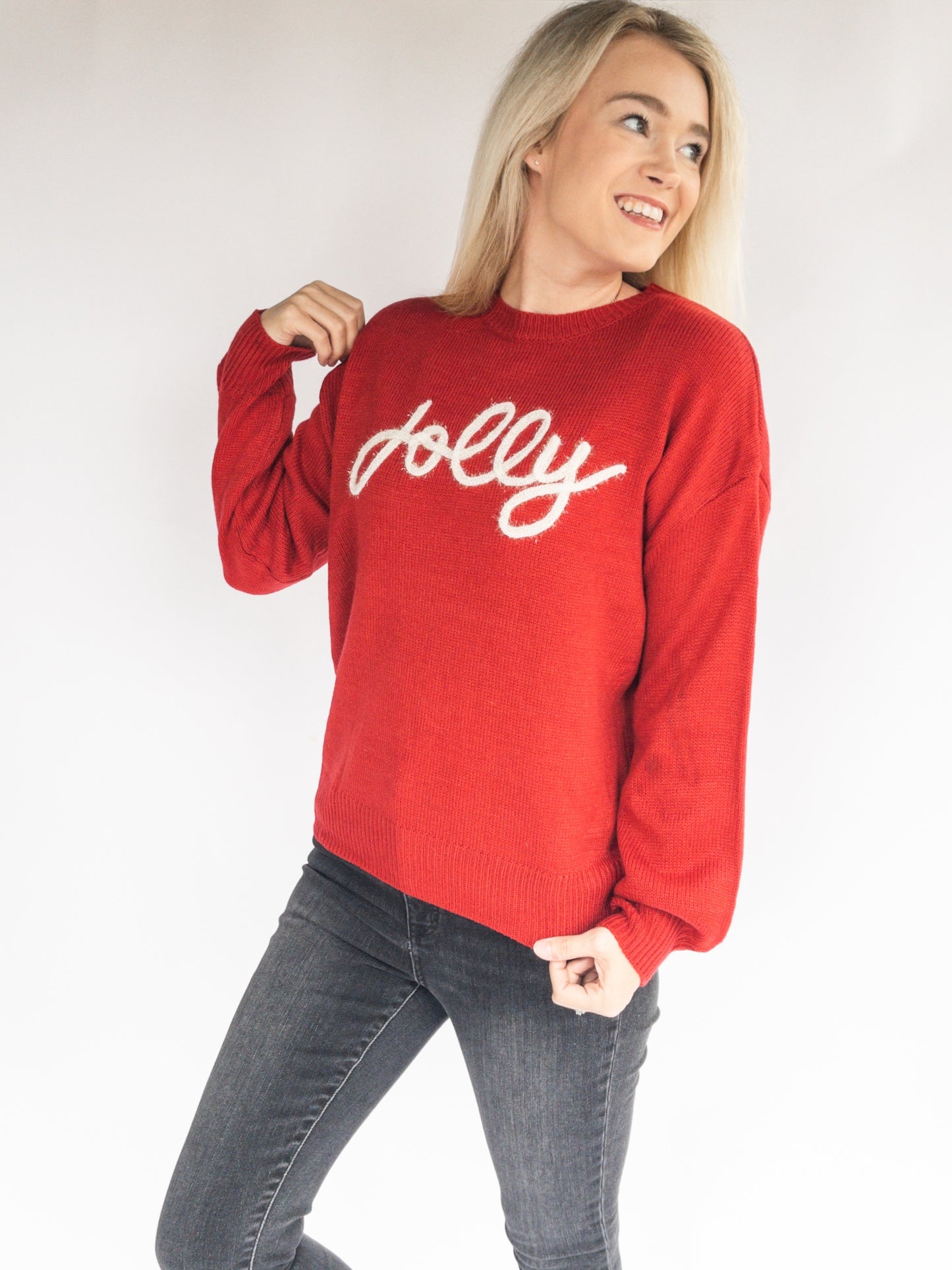 Woman wearing a red christmas sweater with 'jolly' text on a white background