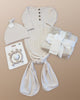 Lou Lou & Company Winnie Gown + Hat clothing and accessories set including a onesie, hat, swaddle, and teether on a beige background.