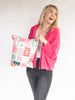 Woman wearing a hot pink cardigan holding a christmas package with a white background